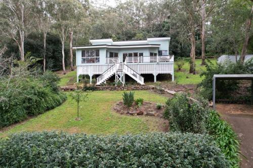 a white house with a porch and a yard at Tree House Toowoomba - Peace & Quiet in tree tops in Preston