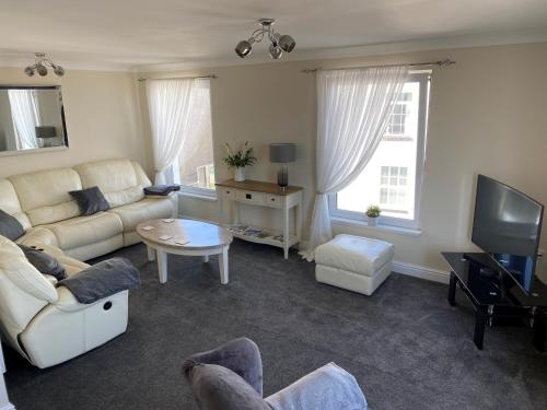 a living room with a couch and a tv at Eastcliffe Penthouse, 2 beds & bathrooms with parking in Cleethorpes