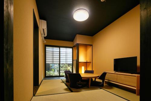 Una sala de estar con una mesa y un televisor. en TSUBOMI luxury Inn Shimabara Bettei 2, en Kioto