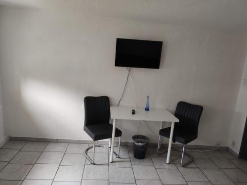 a white table with two chairs and a television on a wall at Schönes einfaches zentrales Zimmer in Oldenburg in Oldenburg