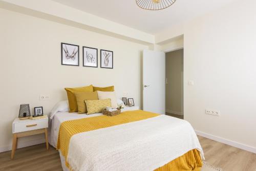biała sypialnia z dużym łóżkiem i żółtym kocem w obiekcie Iluntxo - Soho Center w Maladze