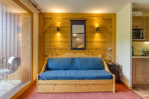 Ce lit bleu se trouve dans une chambre dotée d'un mur en bois. dans l'établissement Les Marmott's, à Villarembert