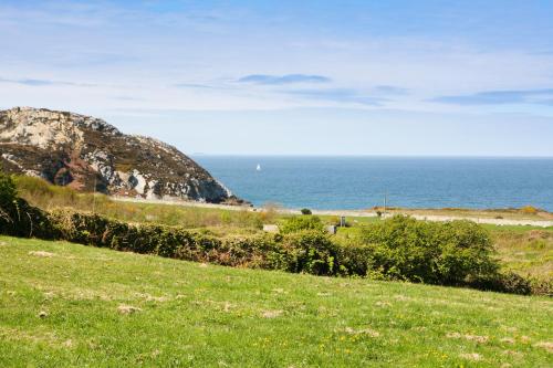 a field of grass with the ocean in the background at Glasfryn in Holyhead