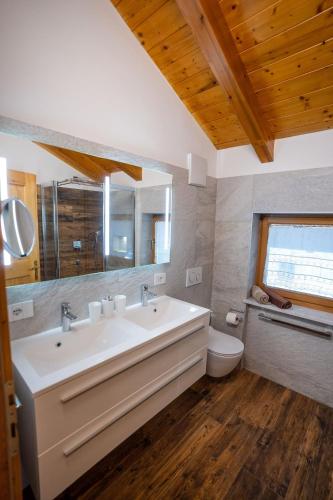 a bathroom with a sink and a toilet and a mirror at Appartamento Bucaneve in Predazzo