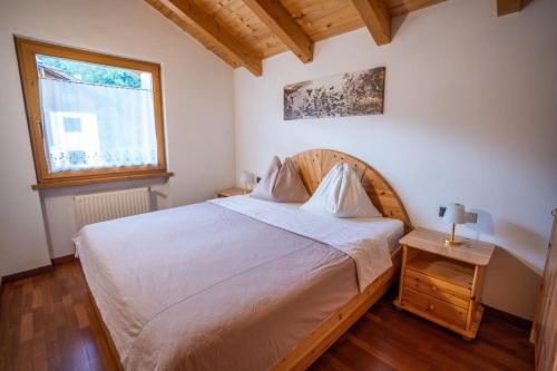 Un dormitorio con una gran cama blanca y una ventana en Appartamento Bucaneve, en Predazzo