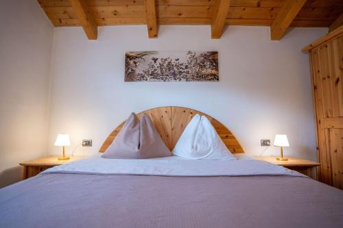 a bedroom with a bed with two lamps on both sides at Appartamento Bucaneve in Predazzo
