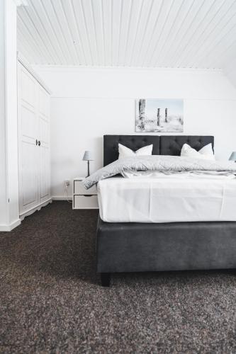 a white bedroom with a large bed with white sheets at Hotel Aurora in Kappeln