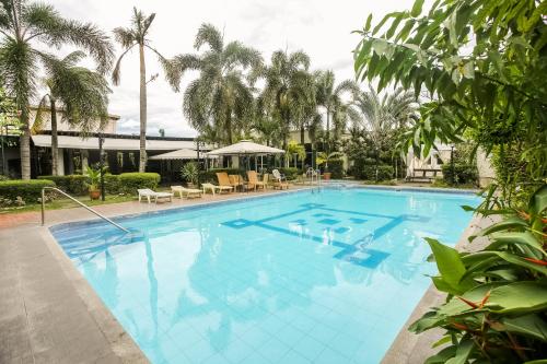 une grande piscine bleue bordée de palmiers dans l'établissement Hotel Euroasia By BLUEBOOKERS, à Ángeles
