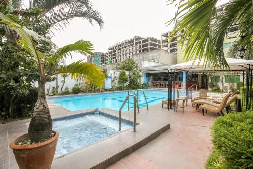 a swimming pool with a palm tree in a courtyard at Hotel Euroasia By BLUEBOOKERS in Angeles
