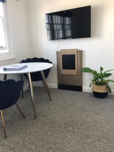 a room with a table and a tv and chairs at SEAFRONT SANCTUARY Beautiful Art Deco Apartment with Stunning City & Sea Views in Brighton & Hove