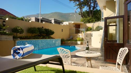 um pátio com uma mesa e cadeiras ao lado de uma piscina em Sundown Manor Guest House na Cidade do Cabo