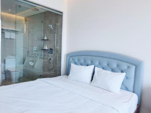 a bed with a blue head board and a shower at Beach Condotel - Apec Phú Yên in Tuy Hoa