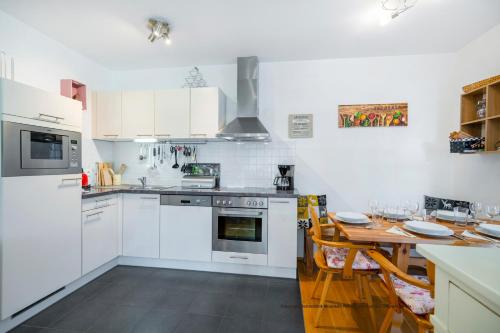 a kitchen with white appliances and a wooden table at Schönblick Mountain Resort & Spa - Das Original! in Rauris