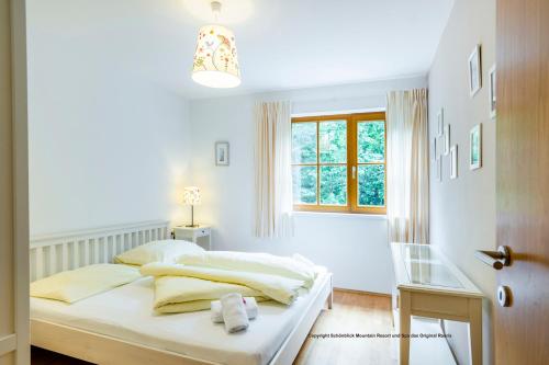 a white bedroom with a bed and a window at Schönblick Mountain Resort & Spa - Das Original! in Rauris
