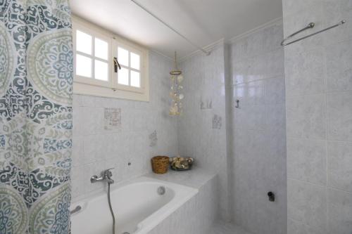 La salle de bains blanche est pourvue d'une baignoire et d'une douche. dans l'établissement The Yellow Art Home, à Kalamata