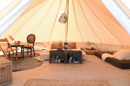a room with a tent with a table and a couch at Smuk Lytse Bell Tent in Echtenerbrug