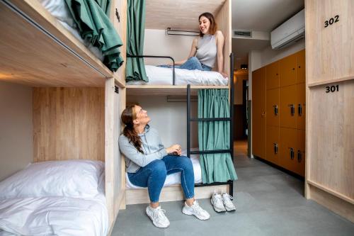 two women sitting on bunk beds in a dorm room at The Bee Hostel in Amsterdam