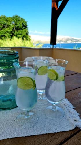 three glasses with lime slices in them on a table at Salt & Stone Villa in Pag