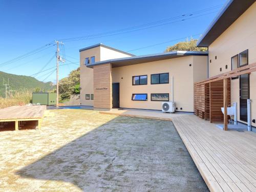 a house with a large backyard with a wooden deck at 柏島ヴィレッジ in Otsuki
