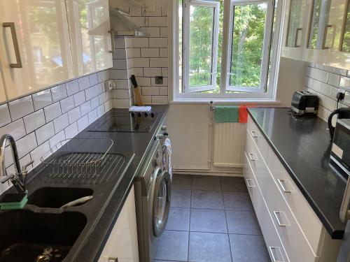 a kitchen with a sink and a washing machine at Beautiful apartment right off of Broadway Market in London