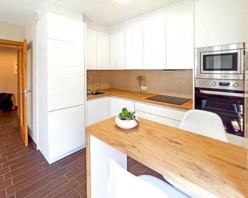 a kitchen with white cabinets and a wooden counter top at Charm apartment in Cambados
