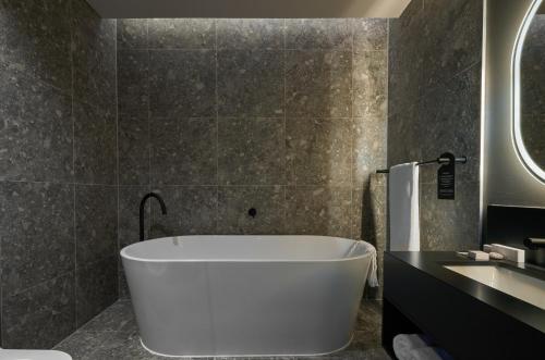 a bathroom with a white tub and a sink at The Rockefeller Hotel by NEWMARK in Cape Town
