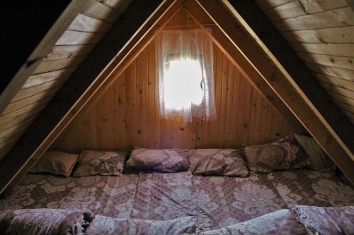 a attic room with a bed and a window at Koliba Nazif Softić in Fojnica