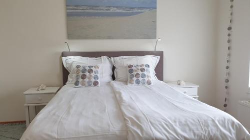 a bedroom with a white bed with pillows and a painting at Florian Studio's in Zandvoort