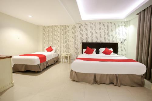a hotel room with two beds with red pillows at Hotel Euroasia By BLUEBOOKERS in Angeles