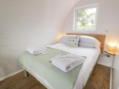 Un dormitorio con una cama con almohadas blancas y una ventana en Laird Lodge 1, en Lockerbie