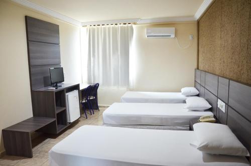 a hotel room with three beds and a television at Inácio Palace Hotel in Rio Branco