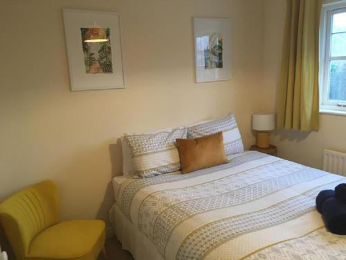 a bedroom with a bed and a yellow chair at KB21 Attractive 2 Bed House, pets/long stays with easy links to London, Brighton and Gatwick in Roffey