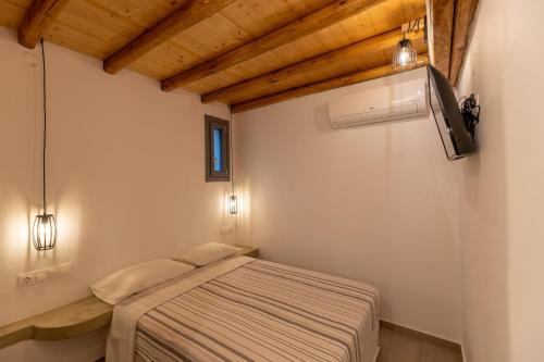 1 dormitorio con 1 cama en una habitación con techos de madera en Aelia House Serifos, en Serifos Chora