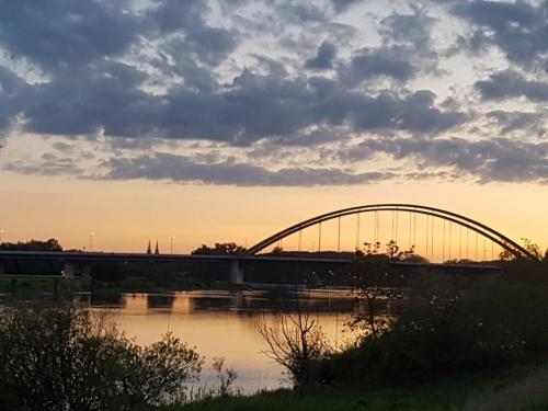 a bridge over a body of water with the sunset at GreenLeaf Walhalla-Apartment - Highspeed WLAN - Netflix - Südbalkon in Tegernheim