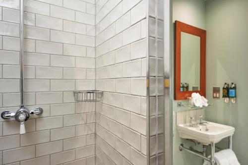 a white tiled bathroom with a sink and a mirror at Hotel du Vin Winchester in Winchester