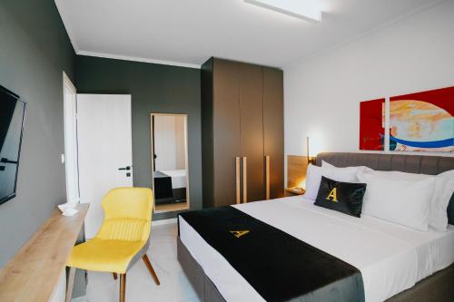 um quarto com uma cama grande e uma cadeira amarela em ALEXANDRA Boutique Residence Downtown em Alexandroúpolis