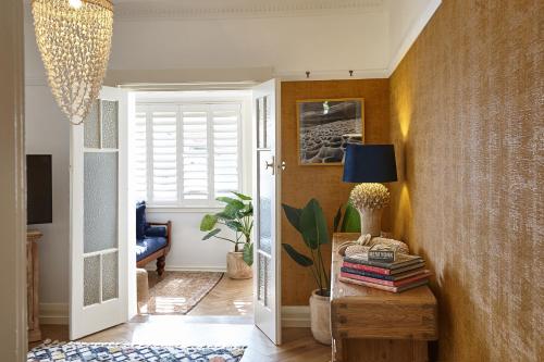 un pasillo con una mesa con libros y una lámpara en kookaburra beach house coogee en Sídney