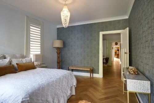 a bedroom with a white bed and a hallway at kookaburra beach house coogee in Sydney