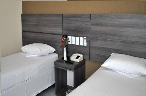 a bedroom with two beds and a phone on a table at Inácio Palace Hotel in Rio Branco