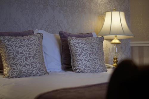 a bedroom with a bed with pillows and a lamp at The Bulkeley Hotel in Beaumaris