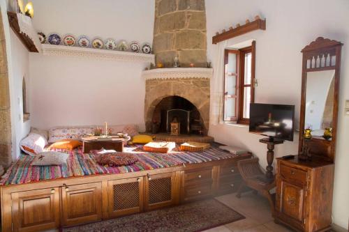 a living room with a fireplace and a television at Matina's traditional house in Haraki