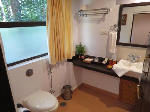 ein Badezimmer mit einem WC, einem Waschbecken und einem Spiegel in der Unterkunft Kanha Jungle Lodge in Dhanwār