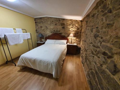 a bedroom with a bed and a stone wall at A Palleira de Aguil in Castro Caldelas
