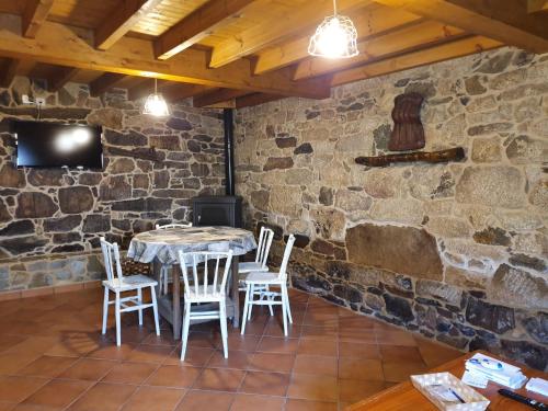 een eetkamer met een tafel en stoelen en een stenen muur bij A Palleira de Aguil in Castro Caldelas