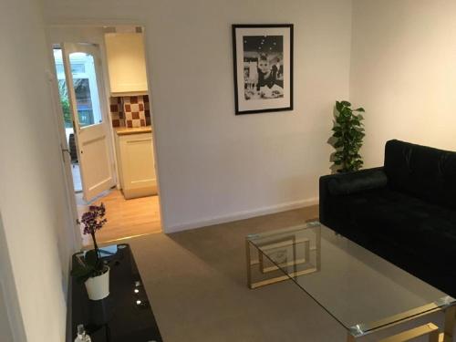 a living room with a black couch and a glass table at KB51 Charming 2 bed house in Horsham, pets very welcome and long stays with easy access to London, Brighton and Gatwick in Warnham