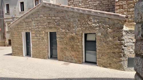 a stone building with three windows on a street at Affittacamere Faber in Tempio Pausania