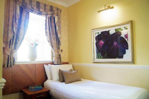 a room with two beds and a window with a picture at The Bulkeley Hotel in Beaumaris
