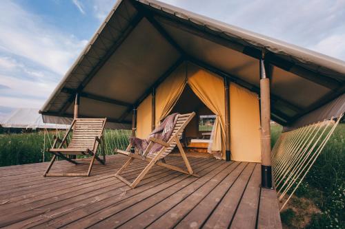 two chairs on a deck in front of a tent at Muuski glempings in Korneti