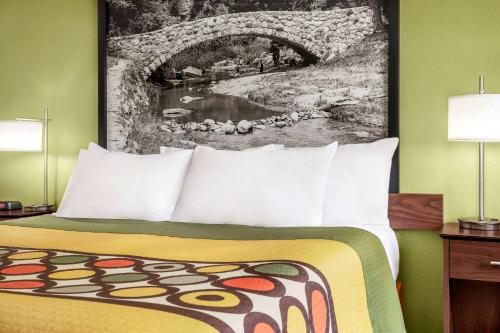 a hotel room with a bed and a painting on the wall at Super 8 by Wyndham Ankeny/Des Moines Area in Ankeny
