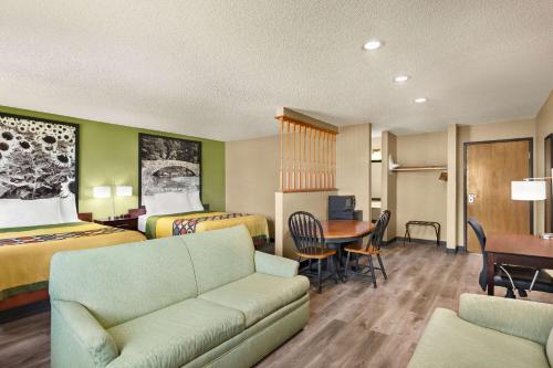 a hotel room with two beds and a couch and a table at Super 8 by Wyndham Ankeny/Des Moines Area in Ankeny